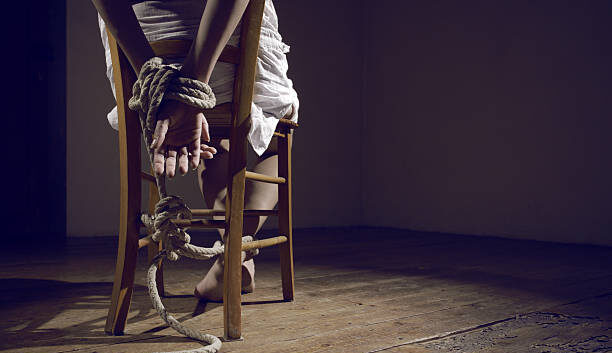 Young woman tied to a chair in a empty room